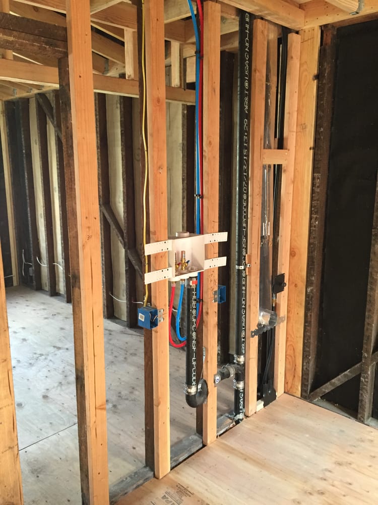 Plumbing rough-in manifold installed cleanly during new construction framing